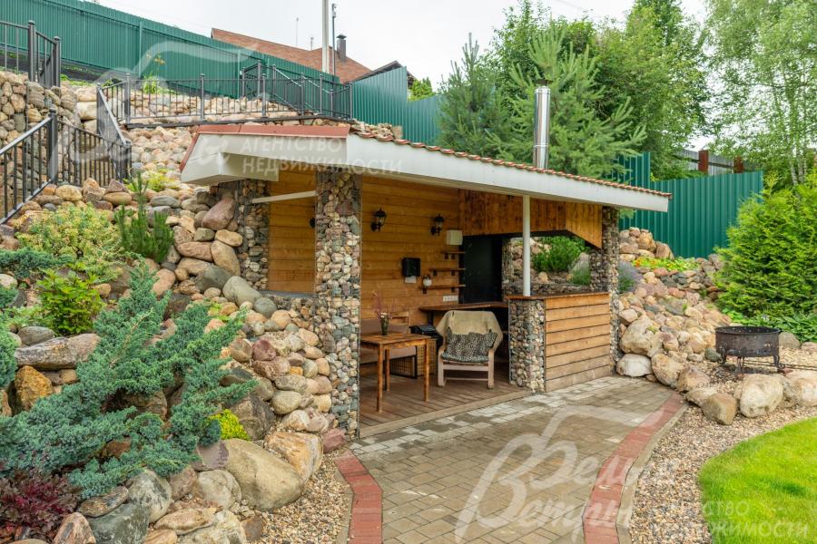 Территория вокруг беседки для барбекю выложена морёным булыжником, справа - костровая чаша